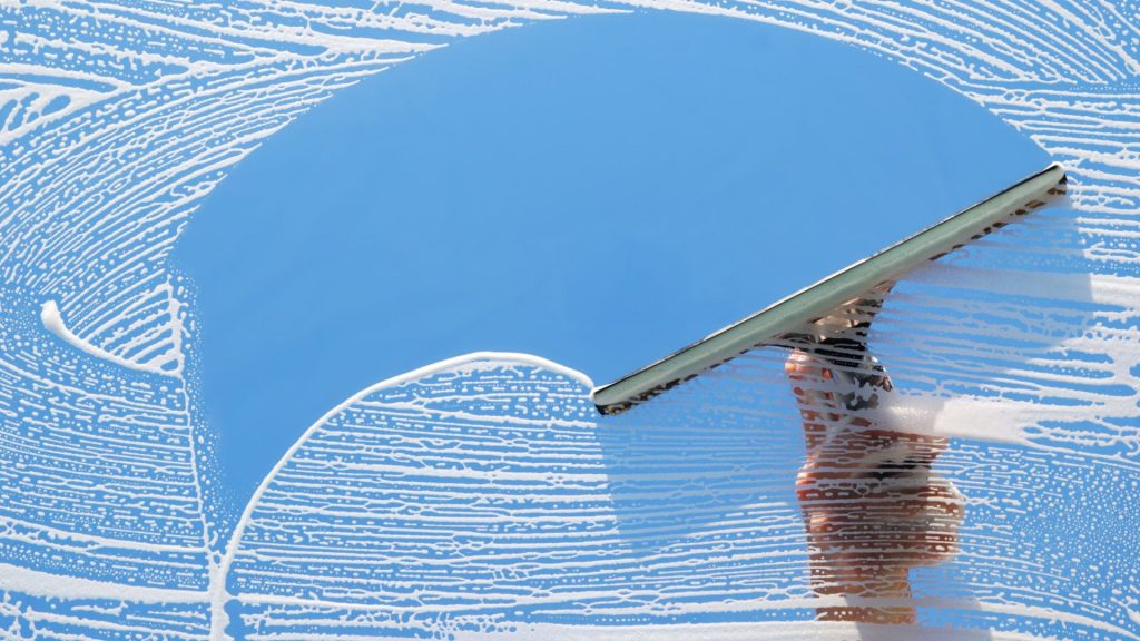 Cristal con jabon e implemento de limpieza.
