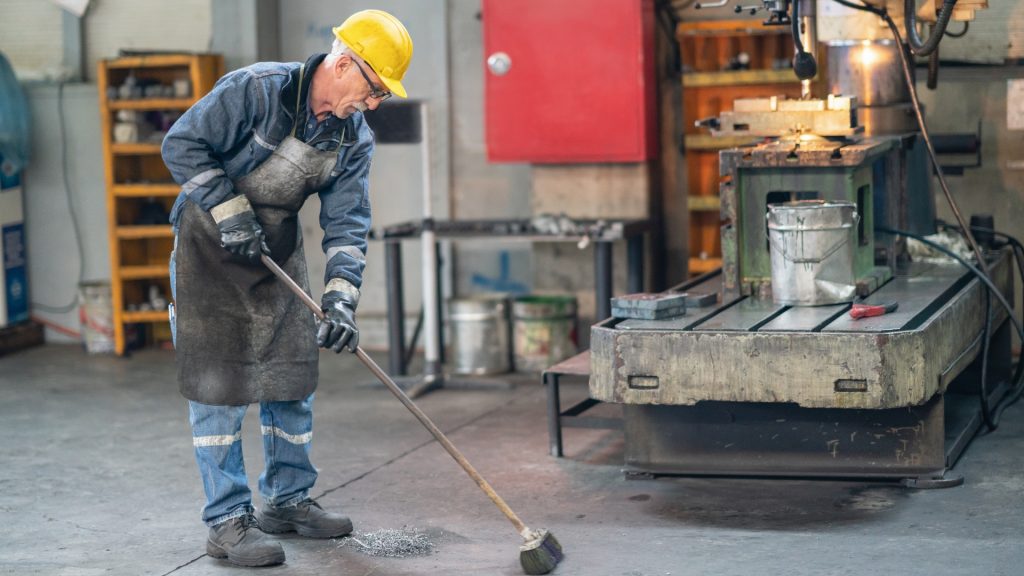 Hombre barriendo una nave industrial
